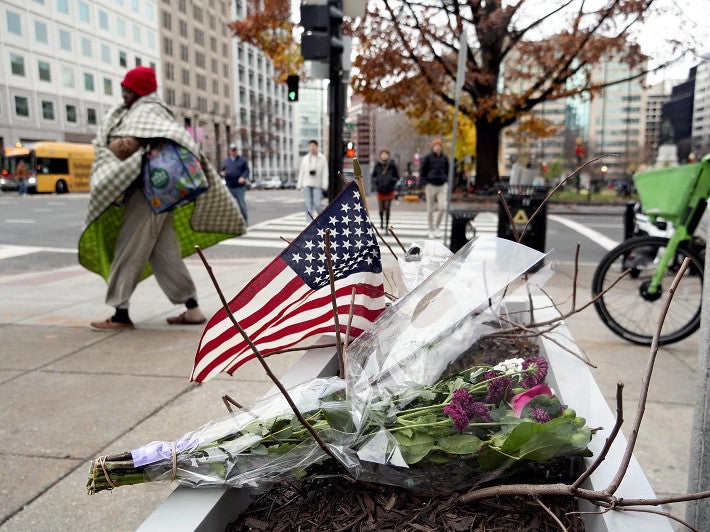 ２７日、米ワシントンで、州兵が銃撃された現場付近に手向けられた花束や星条旗＝中根圭一撮影